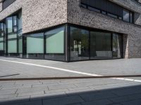 the side view of a modern office building with glass windows and a bench in front