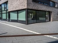 the side view of a modern office building with glass windows and a bench in front