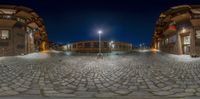 an image of a street with a lot of cobblestone floors and lights on a building