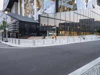 a man walking on a city sidewalk past a glass building with several spires in the background