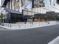 a man walking on a city sidewalk past a glass building with several spires in the background