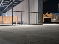 chairs are outside the glass covered windows in this area at night's time light