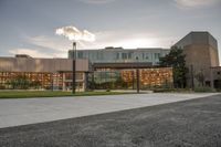 a large building that has a glass and stone facade in it's center of a grassy area near many trees