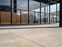 a big building has many glass windows and some wooden panels on the wall outside the doors