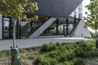 a building with a grass lawn in front of it and trees and bushes on the side of a walkway