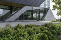 a building with a grass lawn in front of it and trees and bushes on the side of a walkway