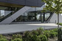 a building with a grass lawn in front of it and trees and bushes on the side of a walkway