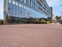 the sidewalk in front of an office building is empty except the sidewalk in front of the building is lined with bricks