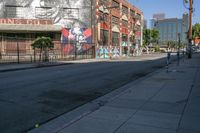 a view down an empty street towards a building with graffiti and another mural on it