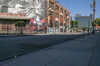 a view down an empty street towards a building with graffiti and another mural on it