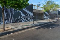 the man on a skateboard is in the street by a mural of elephants on the building's side