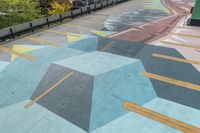 painted walkway on the side of a mountain with city in background next to trees and building