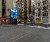 city street in new york with yellow taxi and sign with parking meter on wall near building