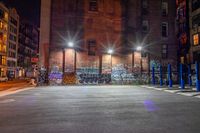 some street lights sitting by a building with graffiti on the walls of it, and blue poles in front