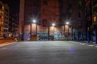 some street lights sitting by a building with graffiti on the walls of it, and blue poles in front