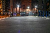 some street lights sitting by a building with graffiti on the walls of it, and blue poles in front