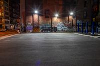 some street lights sitting by a building with graffiti on the walls of it, and blue poles in front