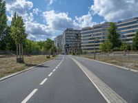 there is an empty street in front of a huge building under construction with trees around