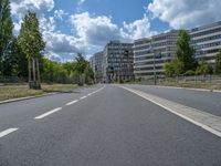 there is an empty street in front of a huge building under construction with trees around