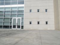 an outside shot of a building with windows and large white door and side walk way