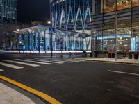 an empty city street next to the entrance of a tall building in the night time