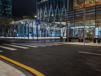 an empty city street next to the entrance of a tall building in the night time