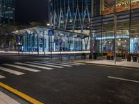 an empty city street next to the entrance of a tall building in the night time