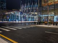 an empty city street next to the entrance of a tall building in the night time