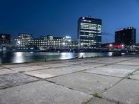 some very pretty tall buildings by the water at night time, taken from near the river