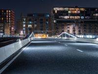 a freeway through a tunnel leading to a tall apartment complex at night, with lights in the sky