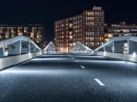 a freeway through a tunnel leading to a tall apartment complex at night, with lights in the sky