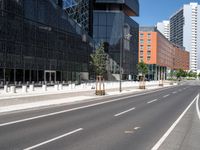 empty city street with buildings behind it with a blue sky in the background, with no cars or pedestrians walking on the pavement