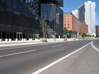 empty city street with buildings behind it with a blue sky in the background, with no cars or pedestrians walking on the pavement