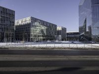 a city view with a bus crossing the road in front of buildings in winter with snow around