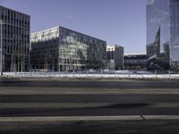 a city view with a bus crossing the road in front of buildings in winter with snow around