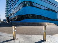 a pair of street poles in front of a building on a city street with cars passing through the road