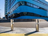 a pair of street poles in front of a building on a city street with cars passing through the road