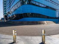 a pair of street poles in front of a building on a city street with cars passing through the road