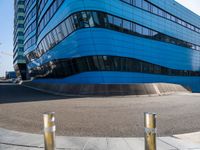 a pair of street poles in front of a building on a city street with cars passing through the road