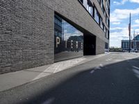 a city street that is empty with buildings reflected in the windows of it behind a brick wall