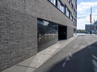 a city street that is empty with buildings reflected in the windows of it behind a brick wall