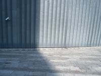 a street light sitting next to a large wall on a brick floor next to a parking meter