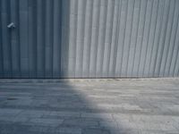 a street light sitting next to a large wall on a brick floor next to a parking meter