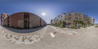 a very wide view of a road taken in a fish eye lens with an orange skateboard on the floor