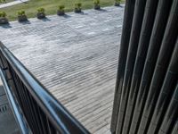 a picture looking down onto a building patio and a green park in the distance, including many plants