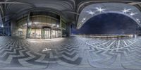 an 360 - ball picture looking towards a circular building at night, with lights reflected on the floor