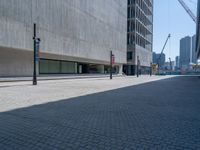 a black traffic light on the sidewalk next to an empty sidewalk with a concrete building