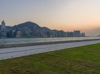 there is a lone person walking on a street next to the water with mountains in the background