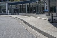 a person sitting at the bench in front of a mall that is empty of people