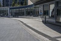 a person sitting at the bench in front of a mall that is empty of people